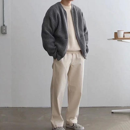 Uomo in abbigliamento casual: cardigan grigio, maglia beige, pantaloni chiari, scarpe a scacchi. Moda autunnale minimalista, stile urbano.