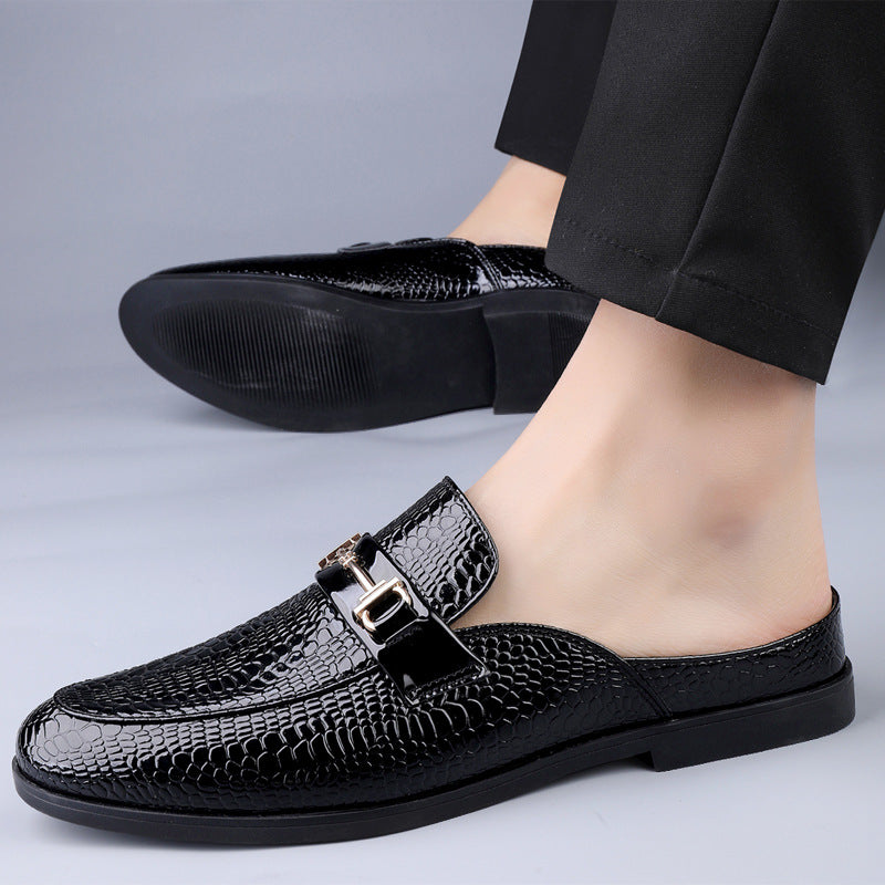 Scarpe mocassini uomo in pelle nera lucida con motivo a serpente, fibbia decorativa, indossate con pantaloni eleganti. Moda calzature maschili.