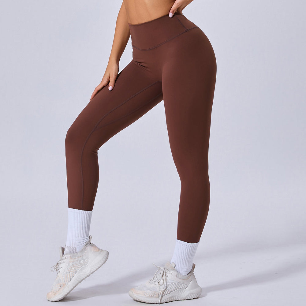 Donna in leggings marroni a vita alta, scarpe da ginnastica bianche e calzini sportivi. Abbigliamento fitness, moda sportiva donna.
