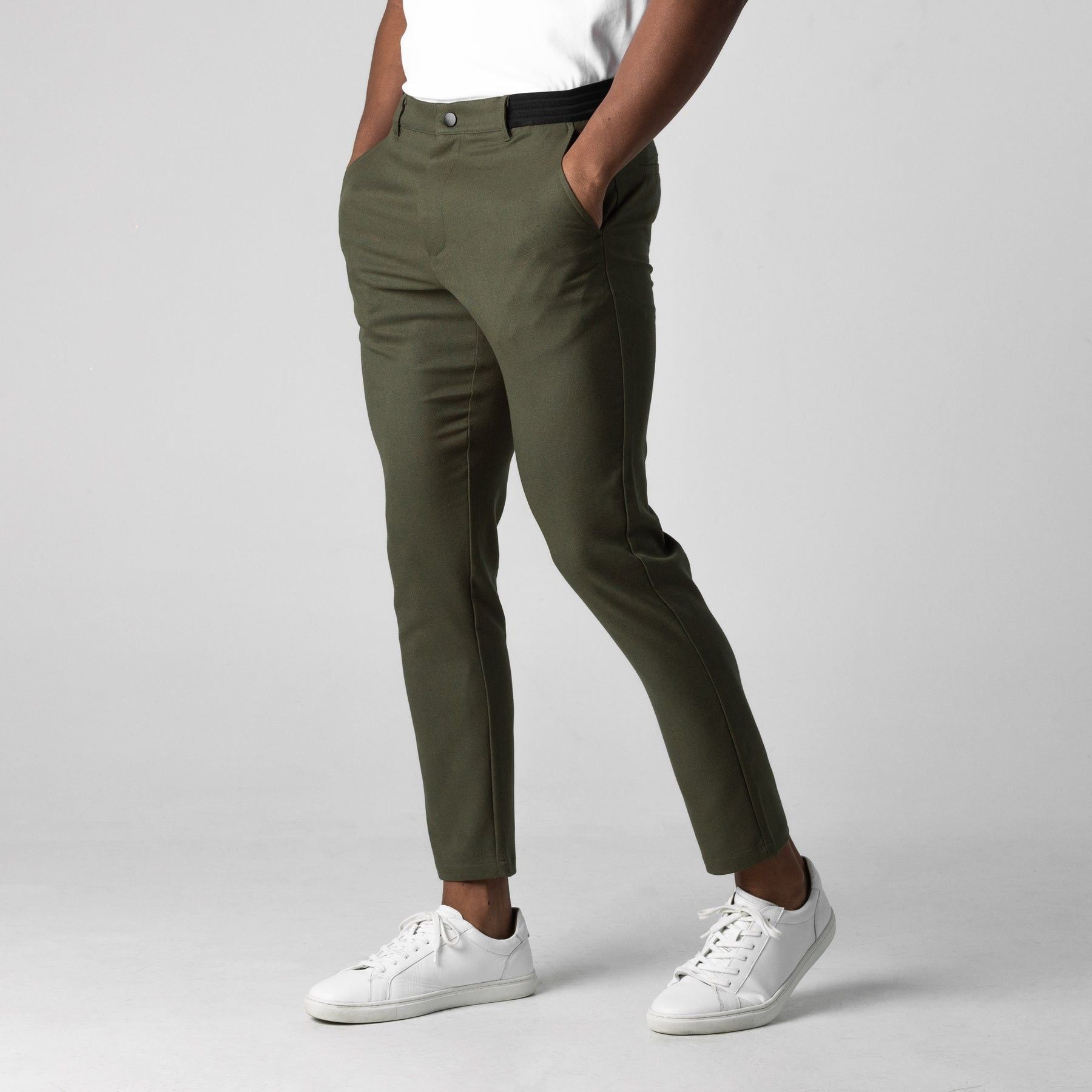Pantaloni chino verde oliva da uomo, abbinati a scarpe da ginnastica bianche e maglietta bianca. Stile casual elegante, moda maschile moderna.