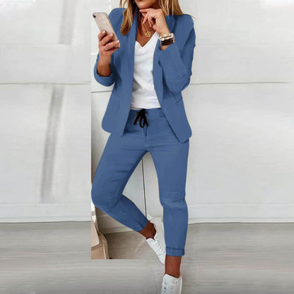 Donna in abito elegante blu, giacca e pantaloni, con smartphone in mano. Look professionale, moda femminile, abbigliamento da ufficio.