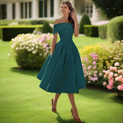 Donna in abito verde elegante su prato fiorito, cammina sorridente. Moda femminile, abbigliamento estivo, giardino fiorito, stile sofisticato.