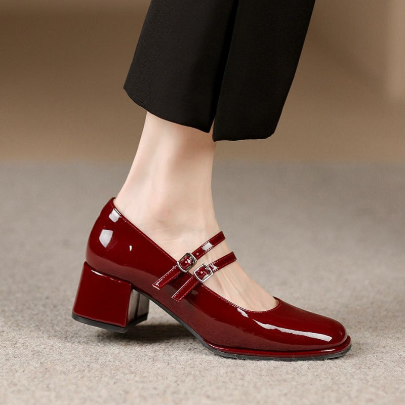 Scarpe rosse lucide con tacco medio e doppio cinturino, indossate con pantaloni neri. Eleganti calzature da donna, moda autunno inverno.