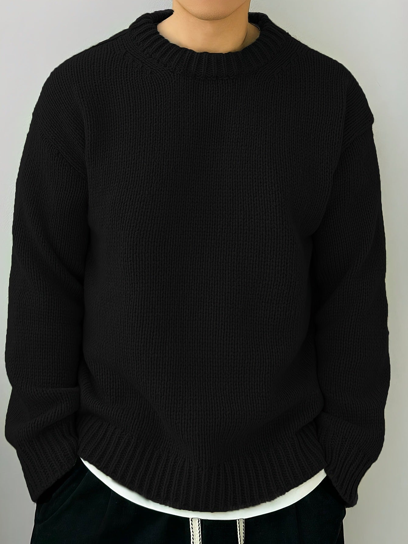 Maglione nero in lana, design a maglia grossa, indossato sopra una maglietta bianca. Moda invernale, abbigliamento casual, stile minimalista.