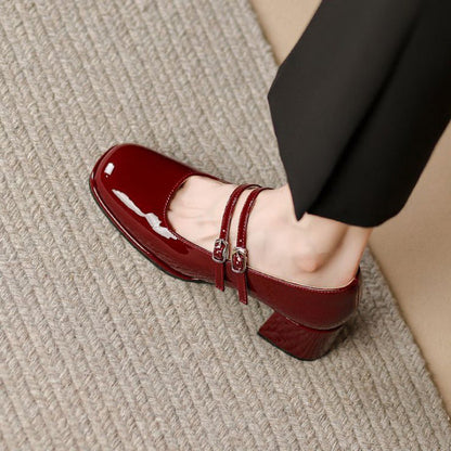 Scarpa Mary Jane in vernice rossa con tacco medio, doppio cinturino, indossata su tappeto beige. Elegante calzatura donna, moda autunno.