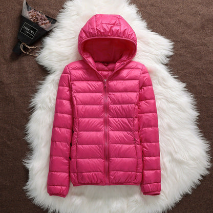 Giacca piumino rosa con cappuccio su tappeto bianco, moda invernale donna, abbigliamento caldo e leggero, stile casual elegante.