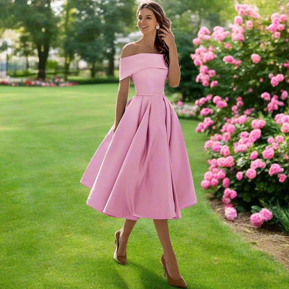 Donna in abito rosa elegante in giardino fiorito, circondata da rose. Moda femminile, abbigliamento estivo, stile sofisticato.
