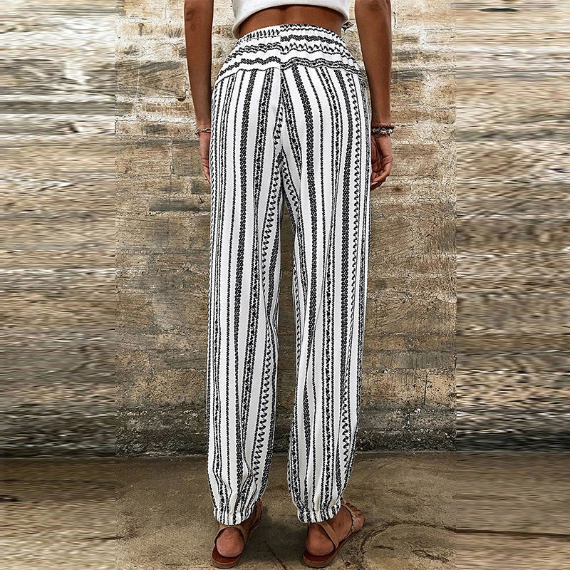 Pantaloni donna a righe bianche e nere, stile boho, con elastico in vita e caviglie, indossati all'aperto. Moda estiva casual.