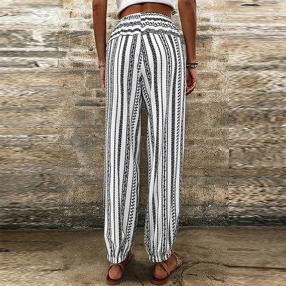 Pantaloni donna a righe bianche e nere, stile boho, con elastico in vita e caviglie, indossati all'aperto. Moda estiva casual.