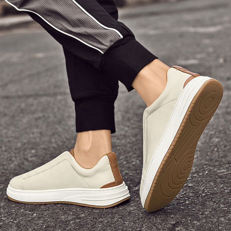 Scarpe da ginnastica beige da uomo su strada asfaltata, design slip-on, suola in gomma marrone, pantaloni sportivi neri. Moda casual, comfort urbano.
