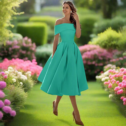 Donna in abito verde smeraldo elegante, cammina in un giardino fiorito con rose rosa, giornata soleggiata, moda femminile, stile estivo.
