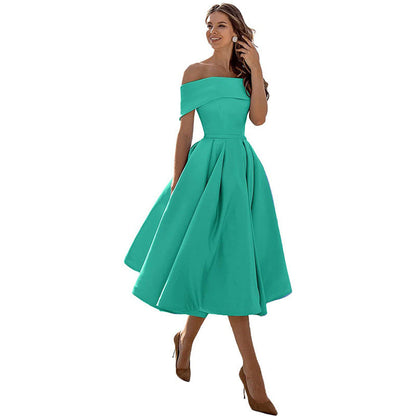 Abito verde smeraldo elegante, spalle scoperte, lunghezza al ginocchio, indossato da una donna sorridente con tacchi alti marroni. Moda femminile chic.