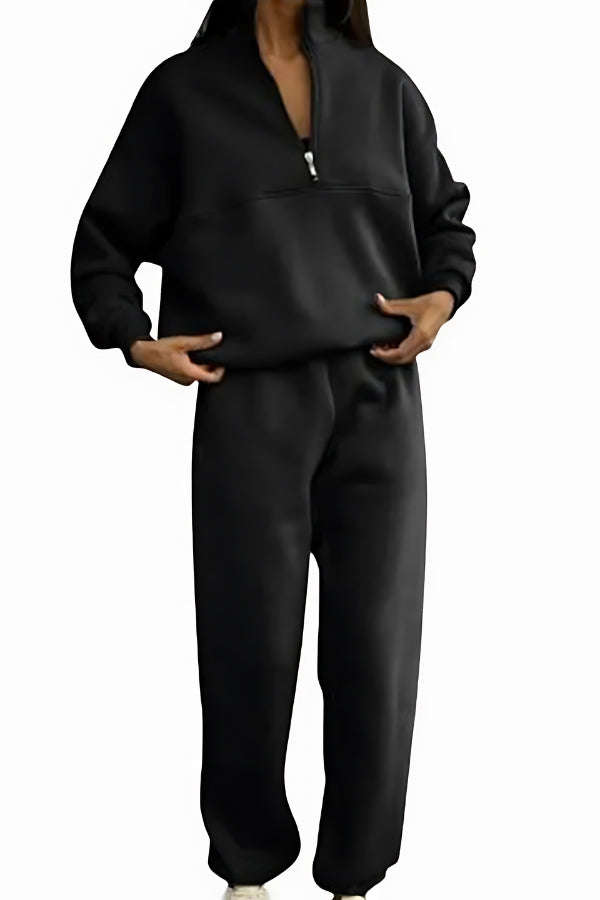 Donna con tuta sportiva nera, felpa con zip e pantaloni larghi. Abbigliamento casual, moda comoda, stile autunnale.