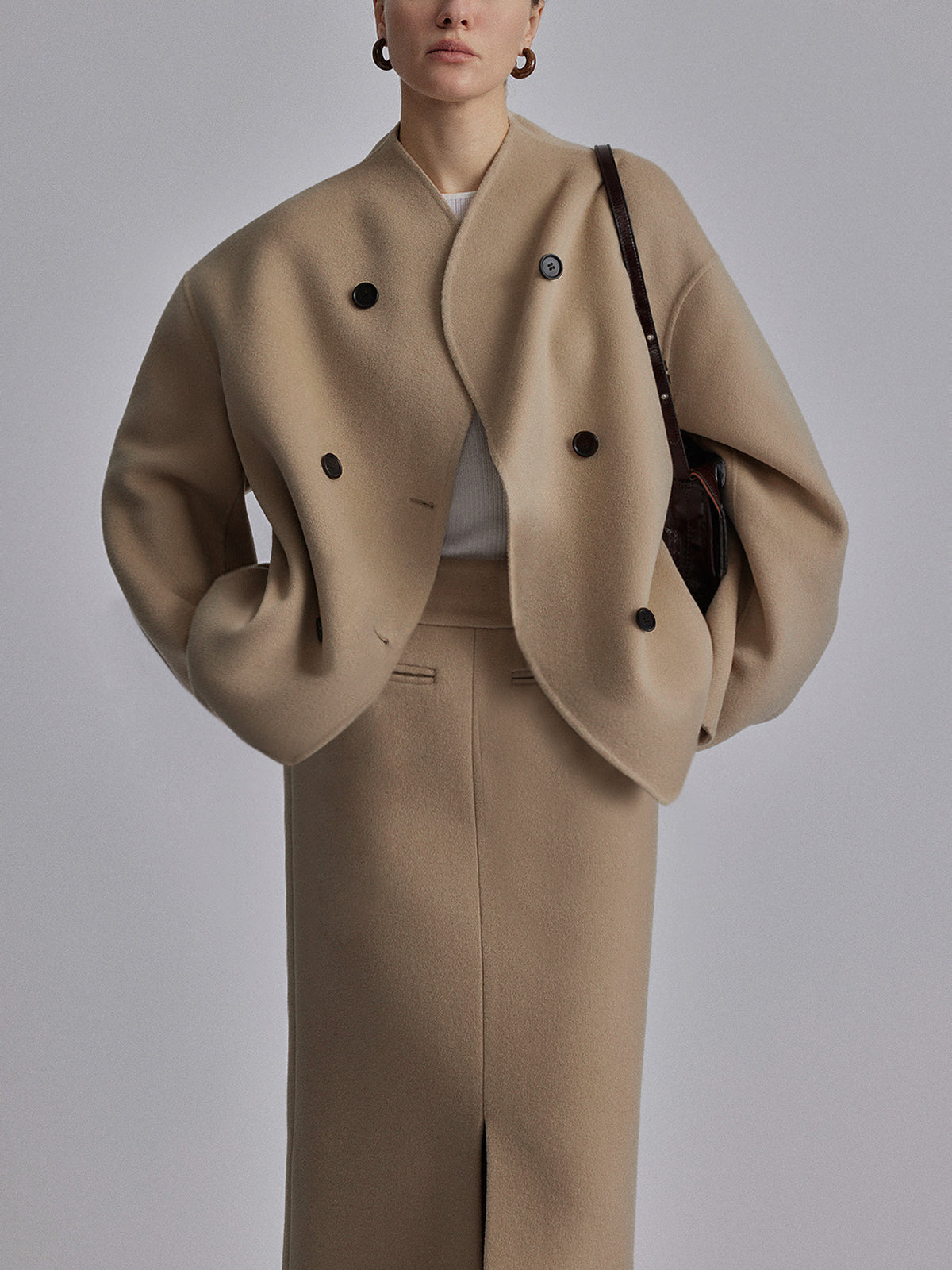 Donna con cappotto oversize beige, abbinato a gonna lunga coordinata. Moda autunno inverno, stile elegante e minimalista.