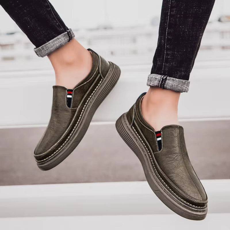 Scarpe slip-on uomo in pelle marrone, suola spessa, indossate con jeans scuri. Calzature casual eleganti, ideali per moda urbana e comfort.
