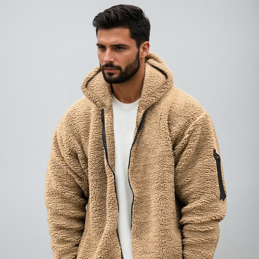 Uomo con giacca in pile beige, cappuccio e zip, su sfondo grigio. Moda autunnale, abbigliamento casual, stile moderno.