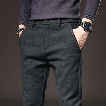 Uomo in pantaloni eleganti grigi, mani in tasca, indossa un orologio nero. Moda maschile, abbigliamento formale, stile contemporaneo.