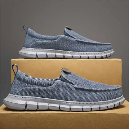 Scarpe slip-on casual grigie da uomo su scatola, suola bianca antiscivolo, tessuto traspirante, ideali per comfort e stile quotidiano.