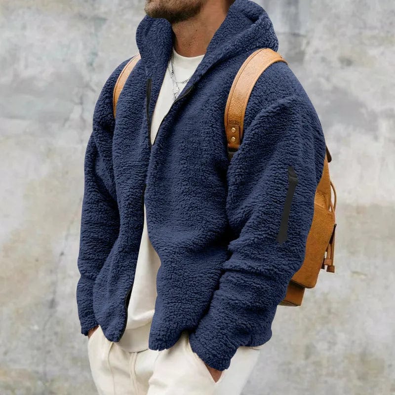 Giacca in pile blu uomo, stile casual, con zaino marrone. Moda autunno inverno, abbigliamento caldo e confortevole. Sfondo grigio urbano.