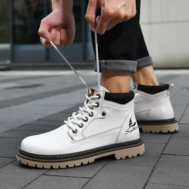 Scarponcini bianchi da uomo, stringati, su pavimento grigio. Design moderno, suola robusta, ideali per moda urbana e comfort quotidiano.