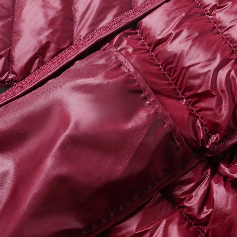 Giacca invernale trapuntata bordeaux, tessuto lucido, dettaglio tasca con cerniera. Moda autunno-inverno, abbigliamento caldo ed elegante.