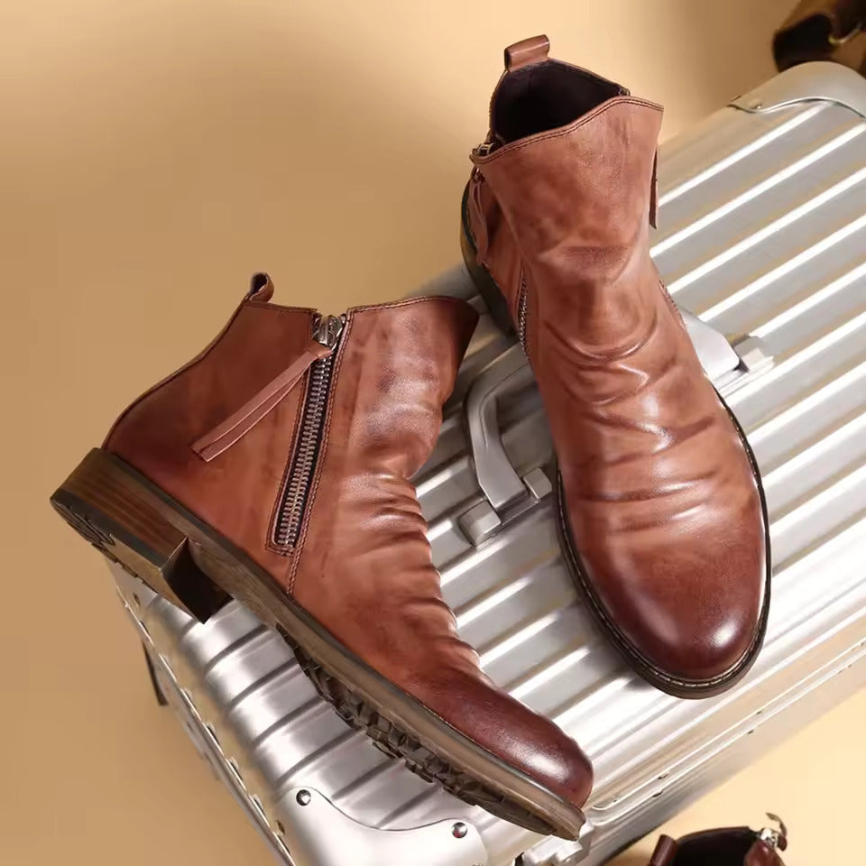 Stivaletti in pelle marrone su valigia argentata, moda autunno, calzature eleganti uomo, chiusura con cerniera, suola robusta.