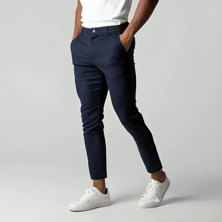 Pantaloni chino blu scuro da uomo, abbinati a scarpe da ginnastica bianche e maglietta bianca, su sfondo grigio chiaro. Moda casual elegante.