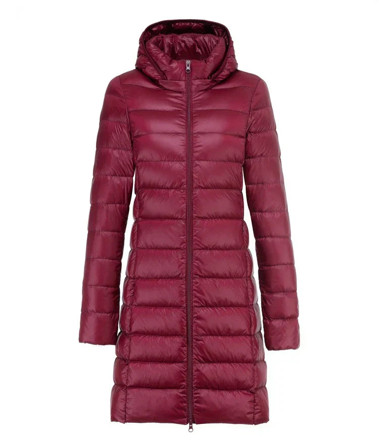 Piumino lungo donna bordeaux con cappuccio, chiusura a zip, design trapuntato. Giacca invernale elegante e calda, ideale per la stagione fredda.