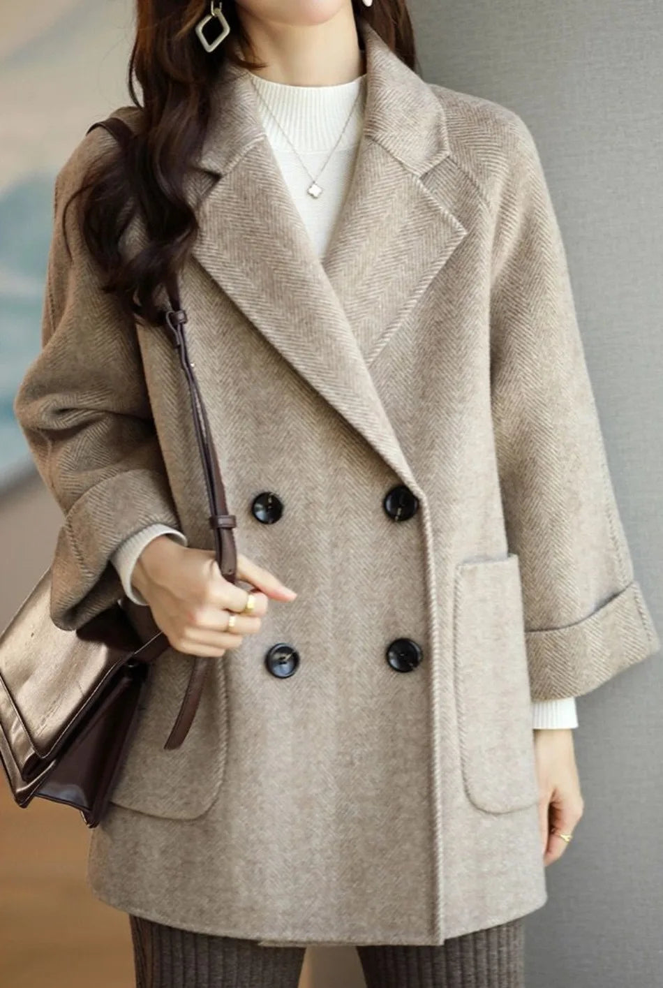 Donna con cappotto beige a doppio petto, borsa marrone, maglione bianco. Moda autunnale elegante, abbigliamento casual chic.