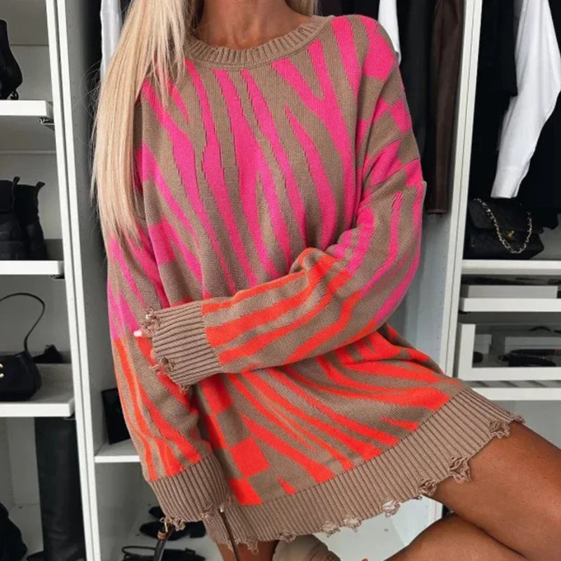 Maglione oversize a righe rosa e arancioni, stile casual, indossato da una donna bionda. Moda autunnale, abbigliamento femminile trendy.