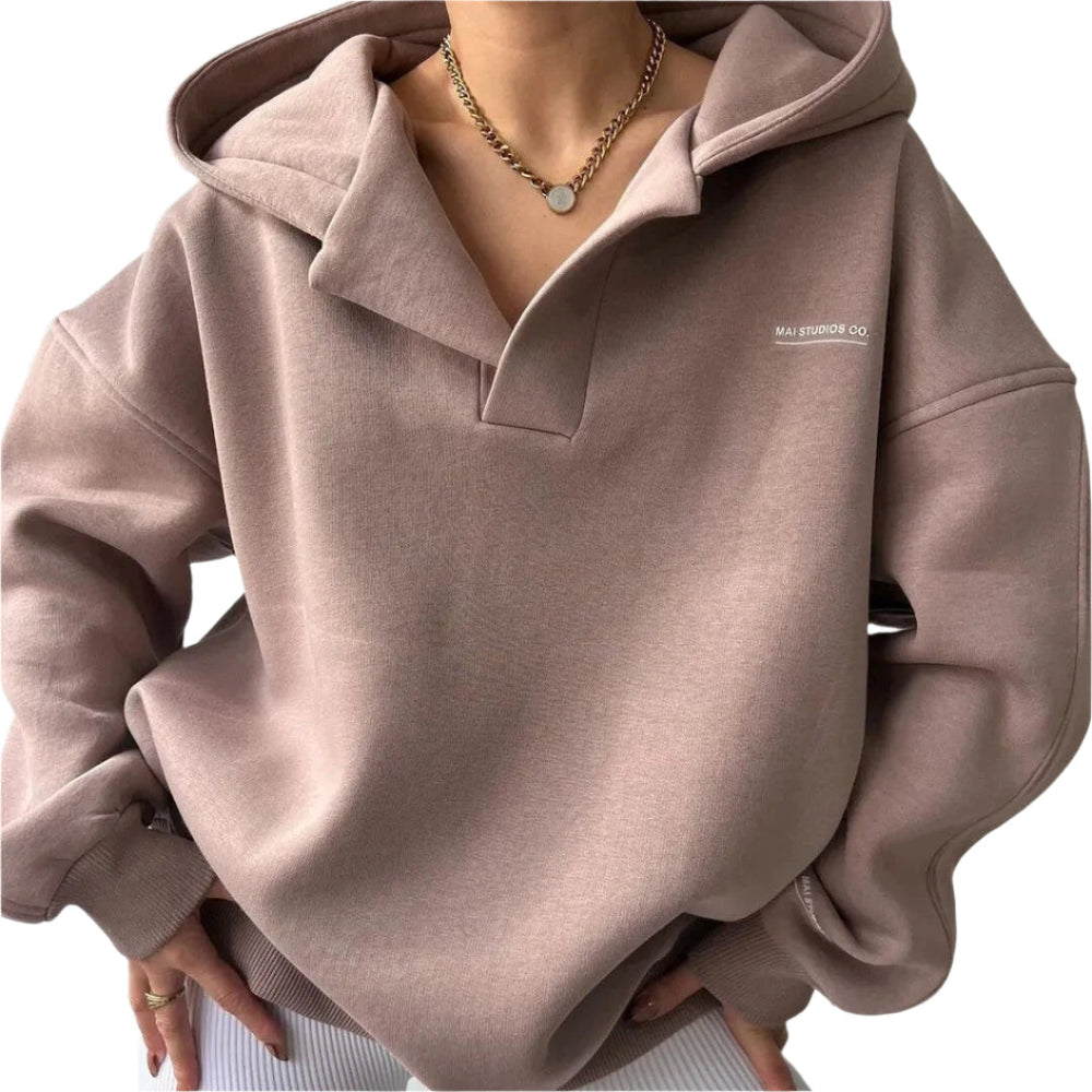 Felpa oversize marrone con cappuccio, indossata da una persona, dettagli in rilievo, catena dorata al collo. Moda casual, abbigliamento autunnale.