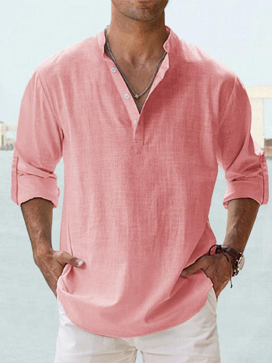 Camicia uomo rosa in lino, maniche lunghe arrotolate, colletto alla coreana, abbinata a pantaloni bianchi. Stile casual estivo elegante.