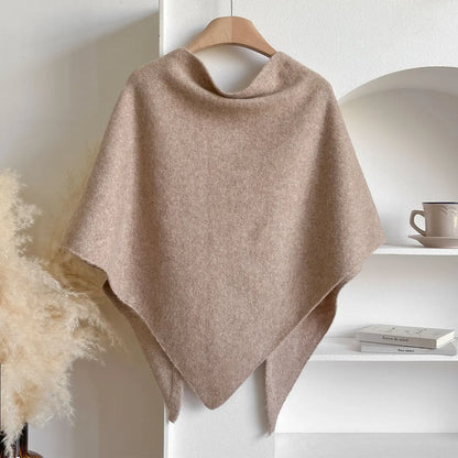 Scialle in cashmere beige appeso su gruccia, sfondo bianco con decorazioni minimaliste. Elegante accessorio moda autunnale.