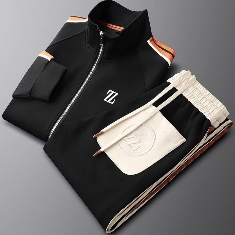 Tuta sportiva nera e bianca con zip, logo su giacca e pantaloni, dettagli arancioni. Abbigliamento atletico di moda, stile moderno ed elegante.