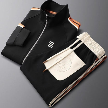 Tuta sportiva nera e bianca con zip, logo su giacca e pantaloni, dettagli arancioni. Abbigliamento atletico di moda, stile moderno ed elegante.