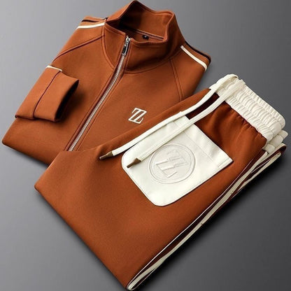 Tuta sportiva marrone con zip e dettagli bianchi, logo su giacca e pantaloni, moda athleisure, abbigliamento casual elegante.