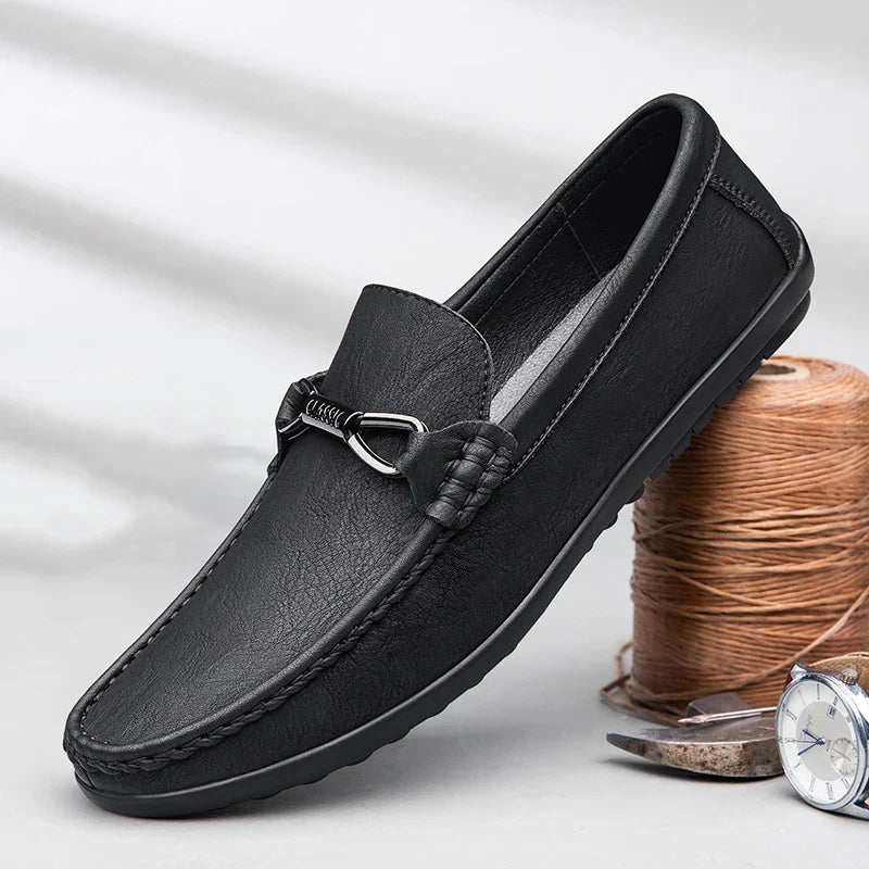 Mocassino uomo in pelle nera con dettaglio metallico, suola antiscivolo. Scarpe eleganti e comode, ideali per look casual e formali.