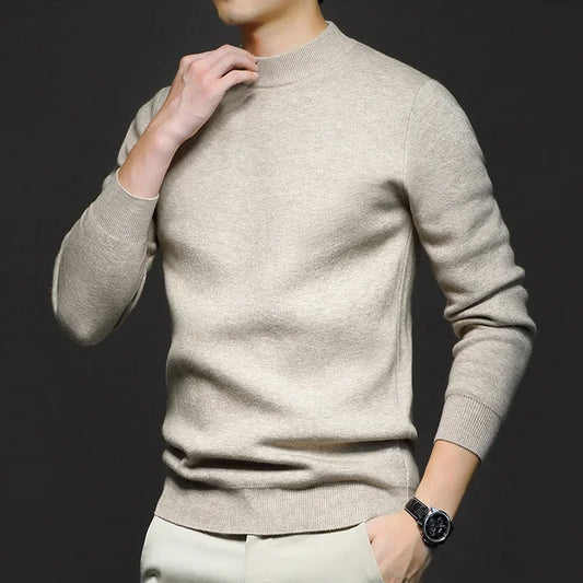 Maglione beige uomo, maniche lunghe, stile casual elegante, indossato con pantaloni chiari. Orologio nero al polso. Sfondo scuro.