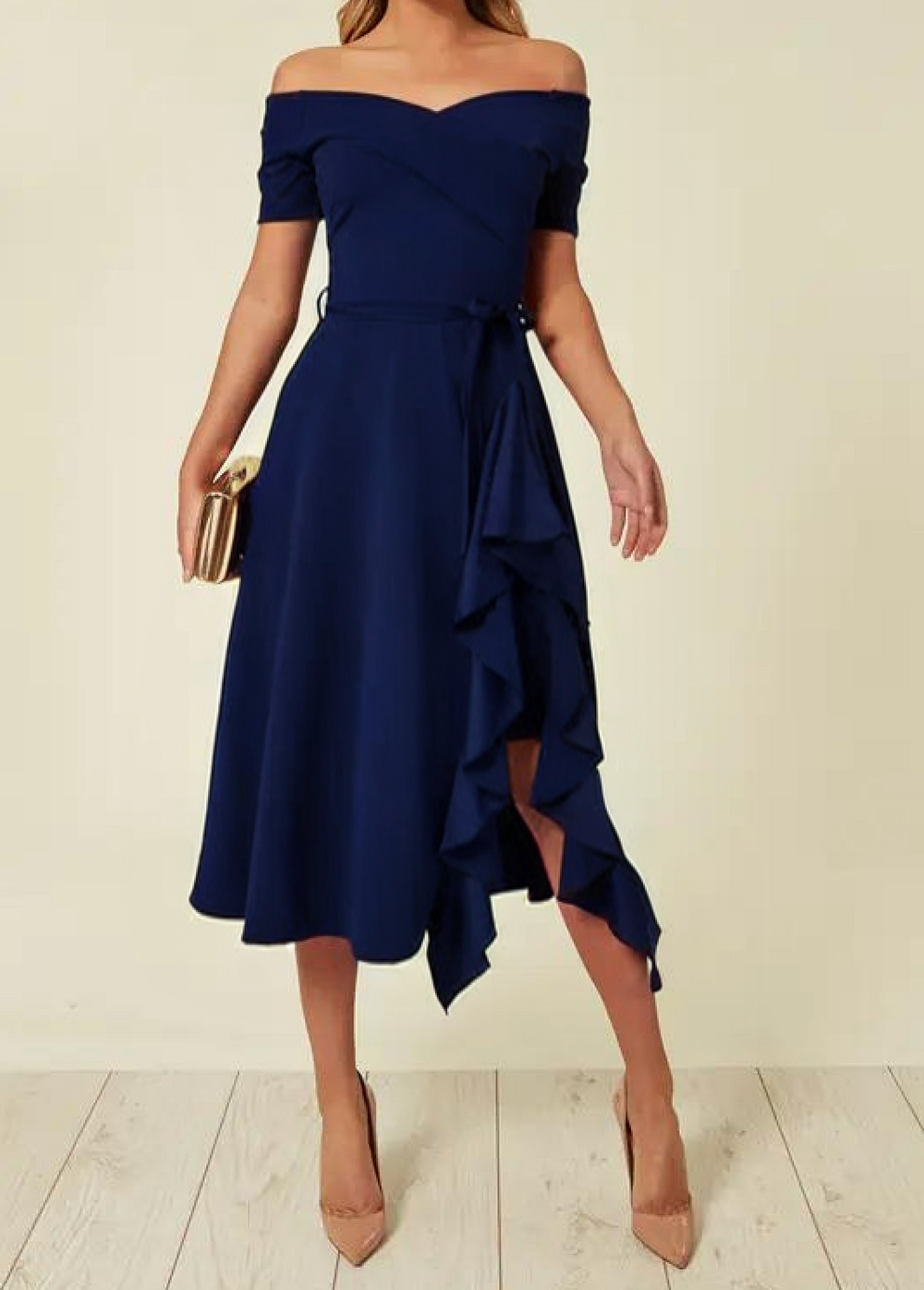 Abito elegante blu scuro con spalle scoperte e volant, lunghezza midi. Accessoriato con pochette dorata e tacchi beige. Moda donna sofisticata.