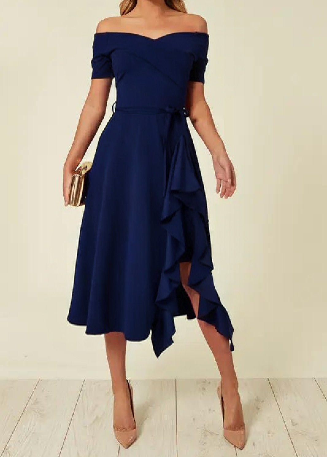 Abito blu elegante con spalle scoperte e volant, clutch dorata, scarpe col tacco nude. Moda donna, abbigliamento da sera, stile sofisticato.