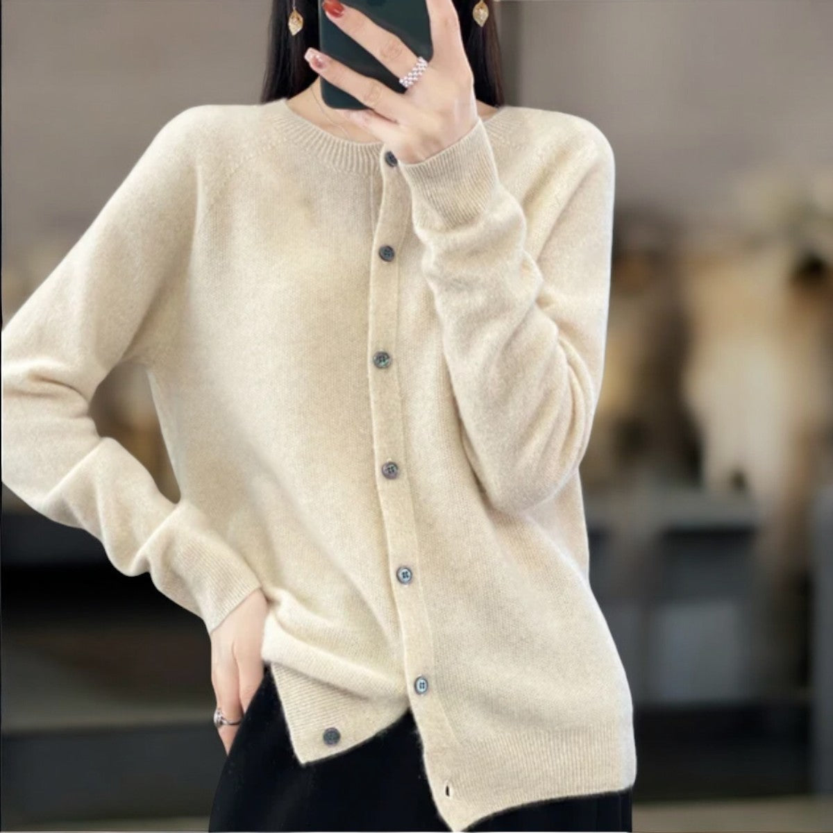 Donna con cardigan beige in cashmere, bottoni frontali, sfondo sfocato. Moda autunno, abbigliamento elegante, stile casual chic.