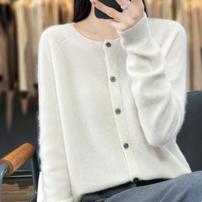 Donna con cardigan bianco in cashmere, seduta su sedia in negozio di abbigliamento. Moda autunnale, stile elegante, abbigliamento femminile di lusso.