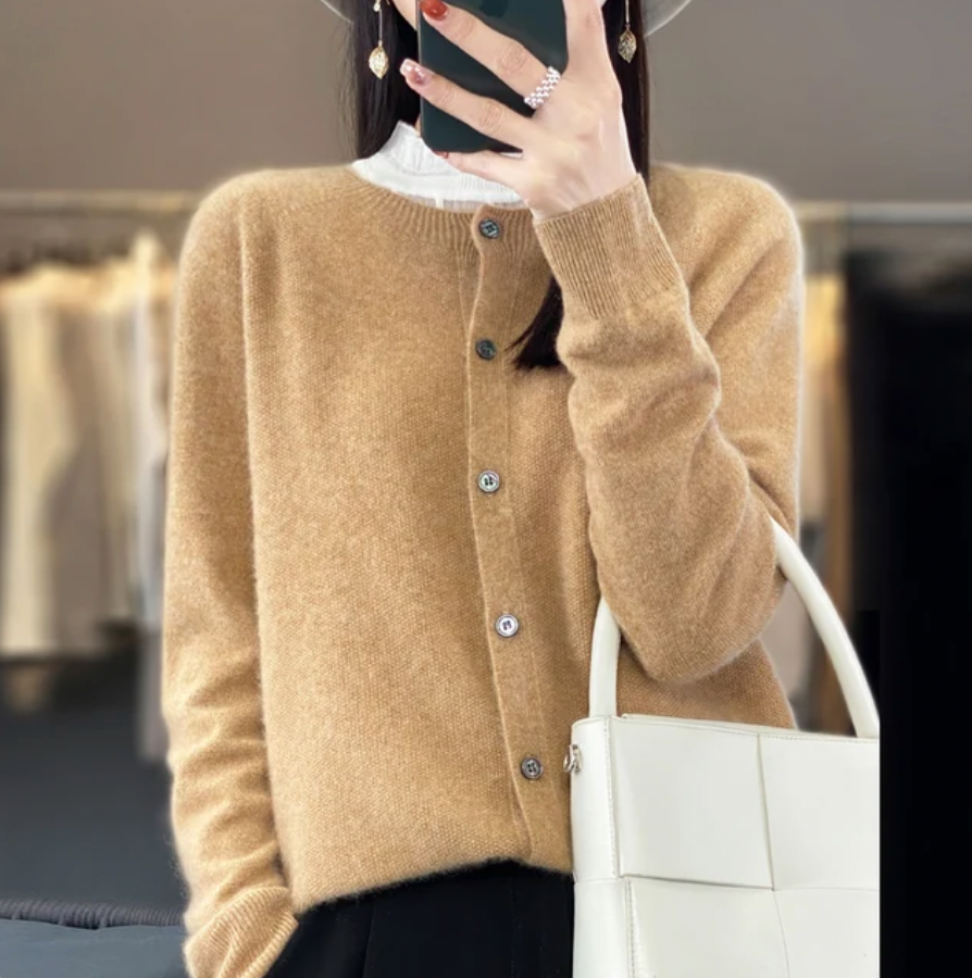 Donna con cardigan beige, cappello grigio e borsa bianca in negozio di moda. Stile autunnale elegante, abbigliamento casual chic.