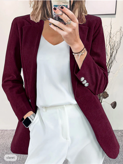 Donna in giacca di velluto a coste bordeaux, camicia bianca e pantaloni coordinati. Moda elegante, abbigliamento autunnale, stile casual chic.