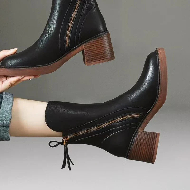 Stivaletti neri in pelle con tacco largo, cerniera laterale e suola marrone. Moda autunno-inverno, calzature eleganti e versatili per donna.