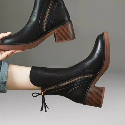 Stivaletti neri in pelle con tacco largo, cerniera laterale e suola marrone. Moda autunno-inverno, calzature eleganti e versatili per donna.