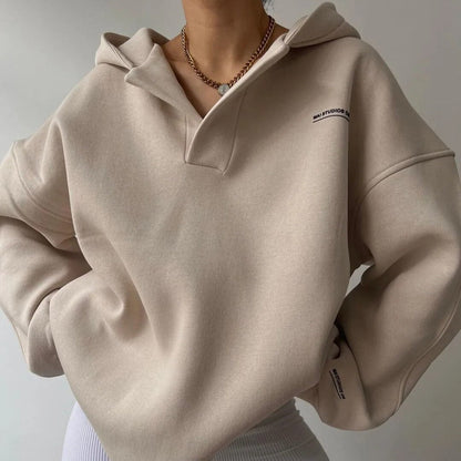 Felpa beige con cappuccio, indossata da una persona, con collana e pantaloni bianchi. Stile casual, moda autunnale, abbigliamento comodo.