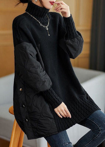 Donna con maglione nero oversize a collo alto, maniche trapuntate, dettagli a bottoni, seduta su sedia. Moda autunno inverno, abbigliamento casual chic.