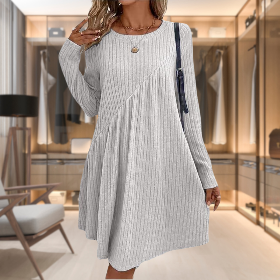 Donna in abito grigio a coste, maniche lunghe, in cabina armadio moderna. Moda femminile elegante, abbigliamento casual chic, tendenze autunno.