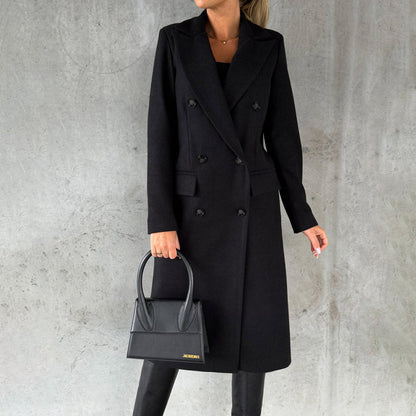 Donna con cappotto nero elegante, borsa a mano nera, sfondo grigio. Moda autunnale, stile sofisticato, abbigliamento femminile chic.